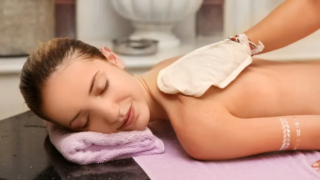 Therapist performing kese exfoliation with silk glove