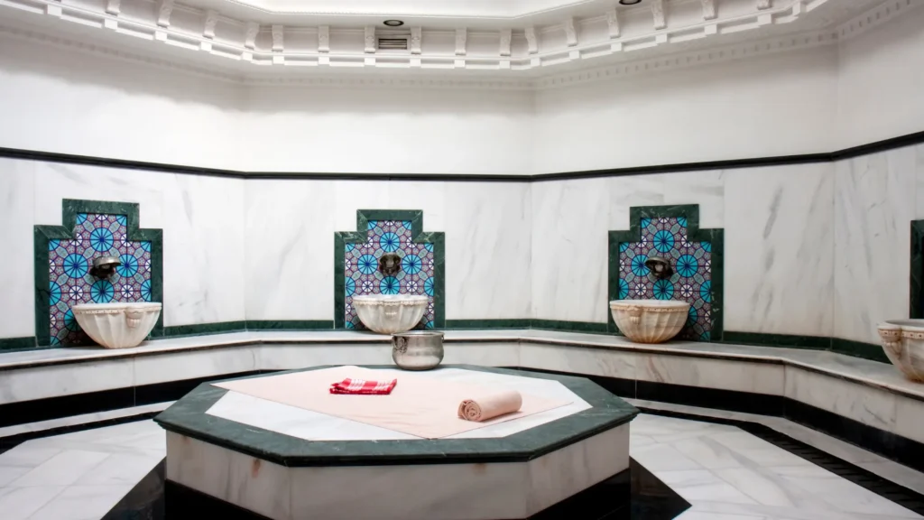 Therapist performing kese exfoliation on heated marble.